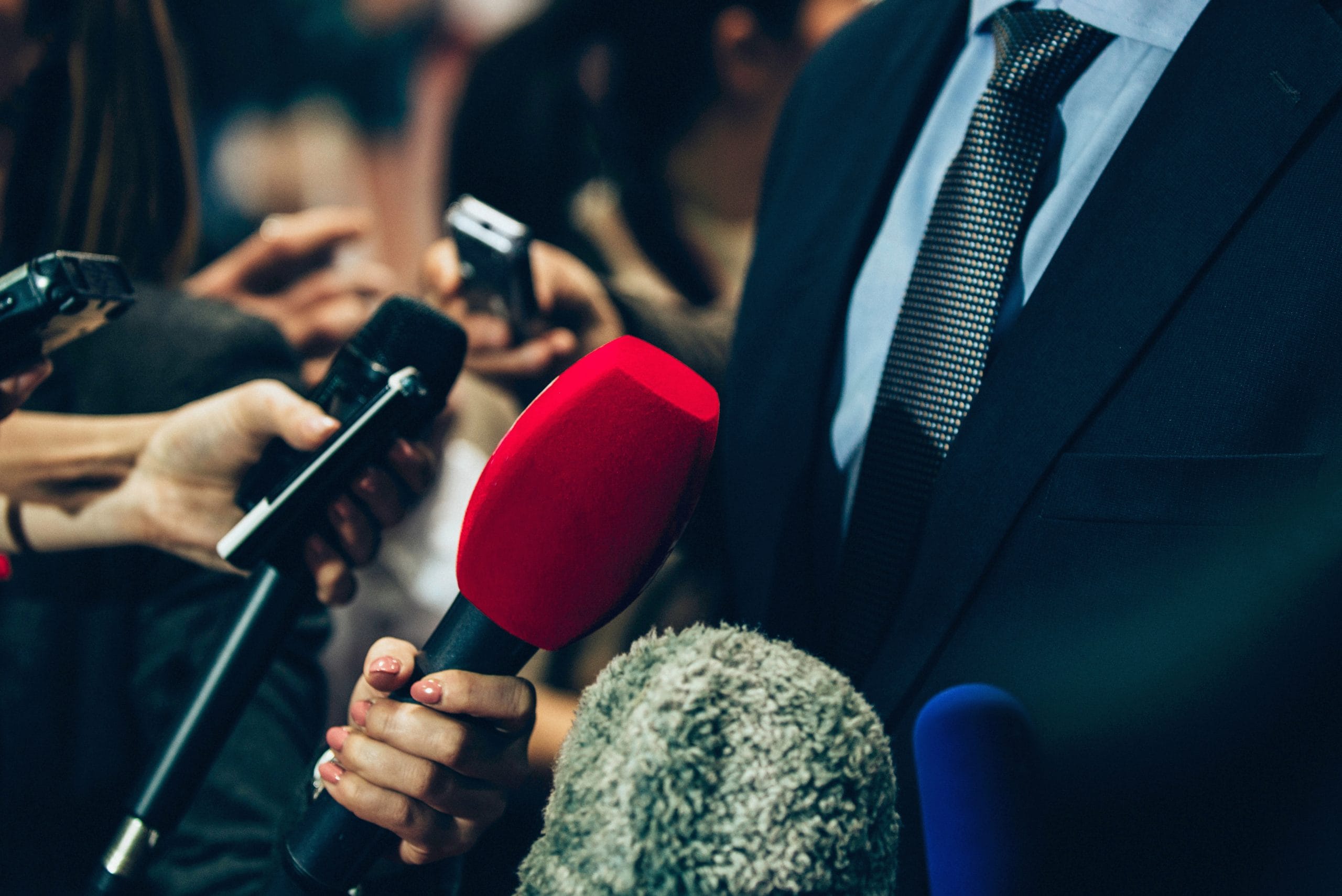 Varios micrófonos apuntando a un hombre